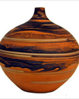 Close-up of small round vase with orange and black marbled design and a narrow neck, ceramic texture visible.