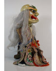 Gray-haired porcelain doll wearing ornate robe, seated against a plain white background.