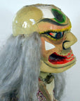 Gray ceramic opera doll with bold makeup and cracked head, side view.