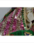 Close-up of pink sequin Taiwan Opera Doll garment with green trim and visible tear near the shoulder seam.