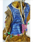 Blue and gold fabric doll with sequins and pink bow, close-up, studio background.