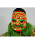 Close-up of Taiwan Opera Doll with bold red, green, and yellow patterns and green hair against a simple background.