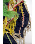 Close-up of Taiwan Opera Doll with yellow fringe, green synthetic hair, zigzag trim, and black and beige fabric.