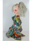 Close-up of Taiwan Opera Doll with white hair, painted face, and green-and-gold sequin clothing.