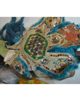 Blue fur-trimmed beaded and sequined doll costume with hand-painted green-face mask, close-up.