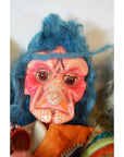 Close-up of a Taiwan Opera Doll with a pink wrinkled face, blue hair, orange outfit, and exaggerated features.