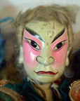 Close-up of a colorful Taiwan Opera Doll, painted face with arched eyebrows and pink cheeks, detailed features visible.