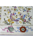White porcelain tall vase with colorful floral and butterfly designs, red and green emblem at base, indoor setting.