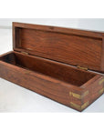 Close-up of an empty hand cut teakwood pencil and jewelry box with brass accents, open lid, on a light surface.