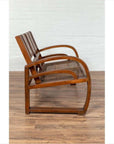 Brown teak wood settee with folding back, looping arms, and cane seat on wooden floor, side view.