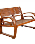 Brown teak wood settee with folding back, looping arms, and cane seat on a white background.