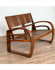 Brown teak wood settee with folding back, looping arms, and cane seat against a white indoor wall.