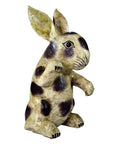 Close-up of a hand-painted ceramic rabbit figurine with upright ears, dark spots, and earthy tones.