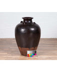 Brown ceramic Thai water jar with handles, early 20th century, on wooden floor with color scale in front.