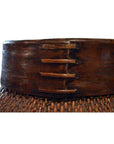 Close-up of natural brown Thai grain basket with wide dark wooden rim and three wooden pegs.