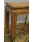 Close-up of brown teak wood Thai table with horse hoof feet on a rustic wooden floor.