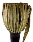 Close-up of a brown leather Thai tribal bongo drum with vertical strips and woven carrying strap in good condition.