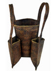 Brown rattan basket made from natural fibers with two straps and three front pockets, close-up view.