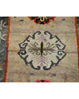 Close-up of a multicolored wool Tibetan praying rug with central floral motif and muted decorative borders, 63" x 36".