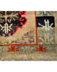 Close-up of Tibetan prayer rug corner, wool, black, red, and beige geometric pattern, fringe visible, good condition.