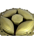 Brass tiered betel nut box with four petal-shaped compartments and a central hexagonal lid, close-up view.