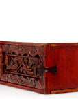 Close-up of red wooden rectangular treasure box with hand-carved raised floral pattern and metal latch on white background.