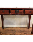 Brown wood triple drawer desk with bronze hardware and horse hoof feet, set on a wooden floor.