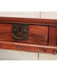 Close-up of antique elmwood desk drawer with metal handle, keyhole, and decorative carvings.