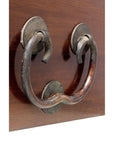 Close-up of a large rustic metal door knocker with a curved handle mounted on natural wood.