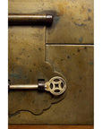 Close-up of an ornate brass key in the lock of a decorative-edged trunk.