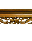 Close-up of brown antique carved wooden table with intricate carvings beneath the tabletop on a white background.