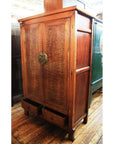 Brown burl wood cabinet with two doors and two open drawers on a wooden floor.