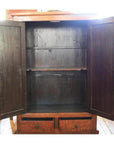 Brown burl wood cabinet with two doors, shelves, and bottom drawers on a wooden floor.