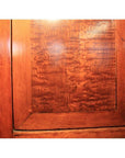 Close-up of brown burl wood cabinet door with unique grain pattern and rectangular frame.