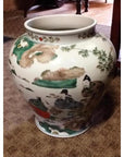 Multicolored painted ceramic urn with Asian figures and nature motifs, displayed on a carpet.