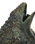 Verde gris bronze pond frog figurine with open mouth and textured skin, close-up on white background.