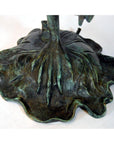 Green patina bronze frog on a leaf base, close-up.