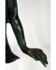 Close-up of green bronze frog statue arm and hand, white background.