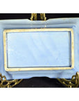 Close-up of blue and white hand painted porcelain dish with raised border, displayed on ornate golden stand.