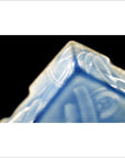 Close-up of blue and white hand painted porcelain dish with intricate patterns, square corner, on black background.