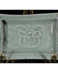 Light blue-green porcelain dish with hand painted geometric border and abstract floral motifs, close-up view.