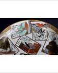 Close-up of vintage hand painted porcelain plate with Japanese artwork and calligraphy on a dark background.