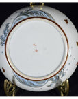 Close-up of base of vintage Asian porcelain plate with blue wave pattern, brown fish, and red Chinese characters at center.