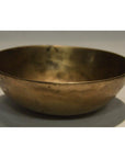 Vintage brass offering bowl with slightly uneven surface on a light background, close-up view.