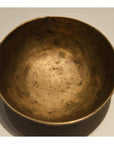 Brass offering bowl with weathered, tarnished surface on light background.