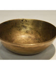 Brass offering bowl with vintage finish on a simple, light-colored surface, close-up view.