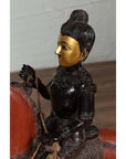 Close-up of black polychrome wooden Burmese warrior statue riding a red horse with gold-painted face.