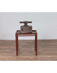 Brown antique book press on vintage Chinese 1950s bamboo side table with patina and recessed top indoors.