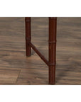 Close-up of two brown bamboo table legs with brownish patina on a wooden floor.