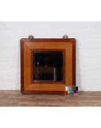 Two-toned elm and rattan square mirror with beveled glass, vintage 1950s Chinese style, against white brick wall.